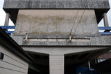 Concrete structure with metal beams and pipes, part of railway station.