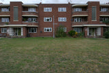Brick apartment building with a grassy area in front
